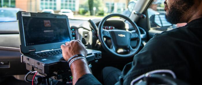 Police officer inside police car looking at the computer.